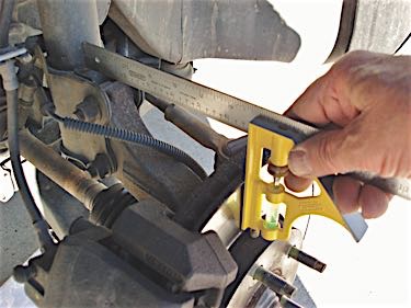 Photo 2: By comparing right- and left- hand side measurements, an adjustable carpenter’s square will quickly reveal a bent strut or steering knuckle.